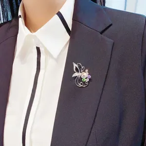 Eleganter Blumen-Schmetterlings-Brosche mit bunten Steinen auf schwarzem Damenblazer