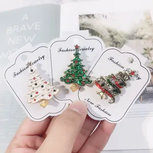 Nahaufnahme von drei bunten, festlichen Weihnachtsbaum-Emaillebroschen mit Glitzersteinen