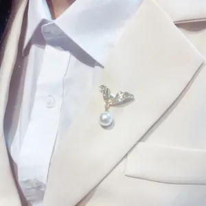 Dettaglio di un'elegante spilla a fiocco con perle sul risvolto di un blazer crema