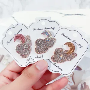 Close-up detail of glittering rhinestone cloud and moon brooches on white display cards