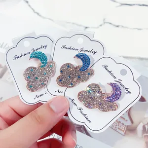 Detailed view of three sparkling cloud and moon brooches with colorful rhinestones