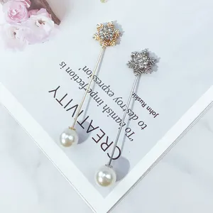 Nahaufnahme eleganter Schneeflocken-Anstecknadeln mit Strass und Perlen auf weißem Magazin