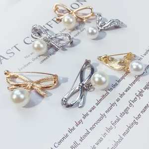 Dettaglio ravvicinato di eleganti spille a fiocco con perle in oro e argento per abiti