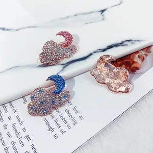 Detail view of sparkly rhinestone cloud and moon brooches with rose gold finish pins