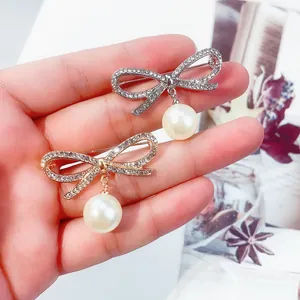 Eleganti spille a fiocco con perle e strass scintillanti in tonalità oro e argento.