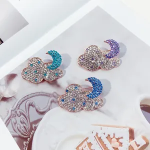 Vibrant rhinestone cloud and moon brooches in teal, purple and blue on an artistic backdrop