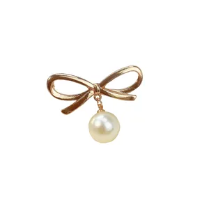 Elegante spilla a fiocco dorata con perla pendente per abbigliamento donna.