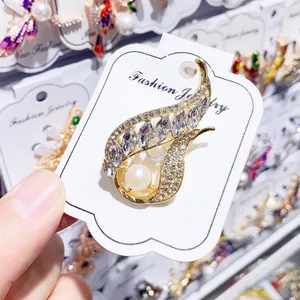 Nahaufnahme einer goldenen Brosche mit Süßwasserperle und funkelnden Kristallen