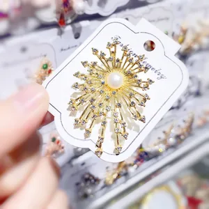 Makro-Detail einer eleganten goldenen Feuerwerksbrosche mit Perle und Strasssteinen.