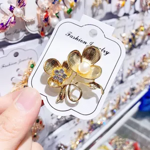 Nahaufnahme einer goldenen Blumenbrosche mit einer Perle und funkelnden Strasssteinen