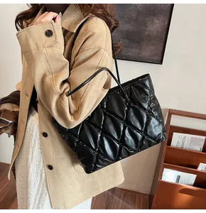 Primer plano de un elegante bolso tote acolchado negro llevado por una modelo con gabardina
