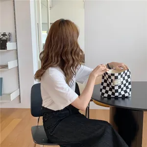 Asian woman looking into a black and white checkered canvas tote bag in a cafe