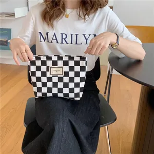 Chic black and white checkered canvas pouch bag being held by a model in a casual interior