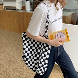 Casual black and white checkered canvas tote bag shown in a lifestyle cafe setting