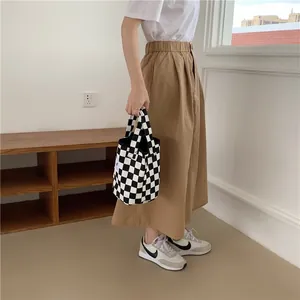 Stylish black and white checkerboard canvas tote bag held by model for casual daily use