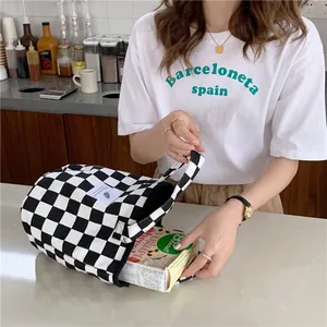 Black and white checkered canvas tote bag shown being filled with items for daily use.