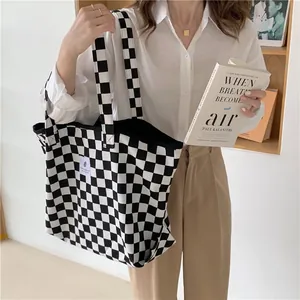Chic black and white checkerboard canvas tote bag carried by a model in a casual setting