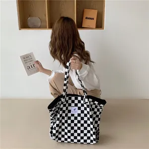 Lifestyle shot of a chic checkerboard canvas tote bag held by a model in a room.