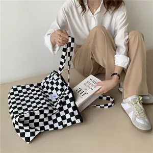 Detail of black and white checkerboard canvas tote bag in a minimalist lifestyle setting