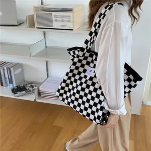 Black and white checkerboard canvas tote bag shown in a lifestyle indoor setting