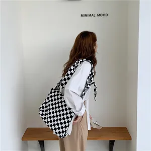 Side view of a woman carrying a large black and white checkered canvas tote bag