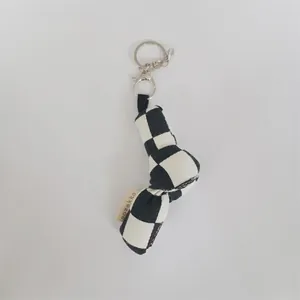 Détail d'un porte-clés chic en toile à damier noir et blanc avec un nœud et anneau métal