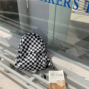 Detailed view of the black and white checkerboard canvas backpack in a lifestyle setting