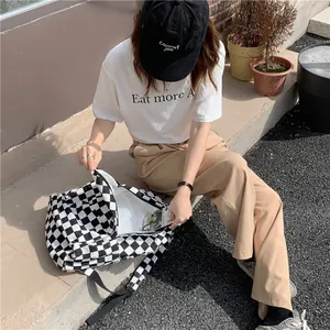 Detail view of a black and white checkerboard canvas bag shown in an outdoor lifestyle setting