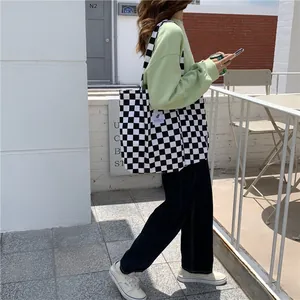 Detailed view of a checkerboard canvas tote bag carried by a model in lifestyle scene