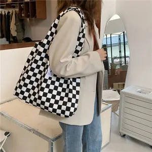 Detail shot of large black and white checkerboard canvas tote bag carried by model
