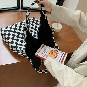 Close-up detail of a black and white checkered canvas tote bag with a book inside