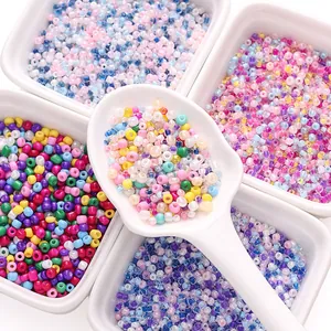 Assorted 2mm colorful glass seed beads in white dishes for DIY jewelry crafting