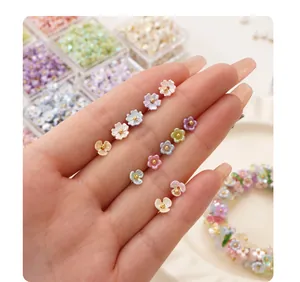 Close-up of colorful resin flower beads with gold centers held in hand for DIY jewelry
