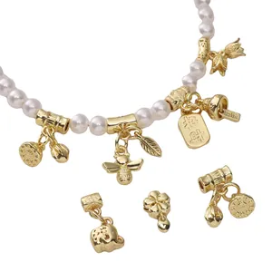 Detail von 14k vergoldeten Anhängern mit Glücksschild und Biene auf Perlenkette