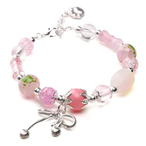 Close-up of a handmade pink glass bead bracelet with a silver alloy bow charm.