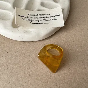 Detail view of an amber resin ring featuring a bold geometric faceted cut design.