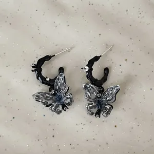 Detailed close-up of dark liquid resin butterfly earrings with clear crystal studs