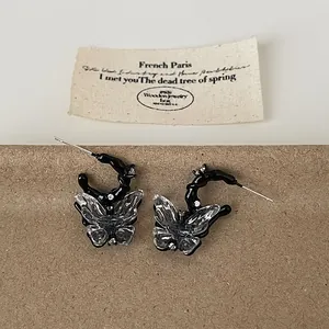 Close-up detail of dark edgy liquid resin butterfly earrings featuring transparent wings