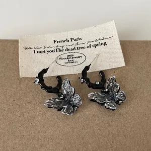 Detailed view of punk style black hoop earrings with clear resin butterfly charms