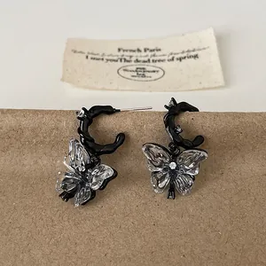 Close-up of liquid resin butterfly earrings with clear wings and black metal finish