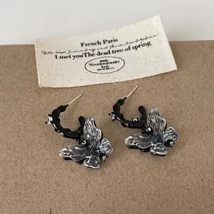 Close-up of black liquid frame butterfly earrings with clear resin wings on a rustic tag.