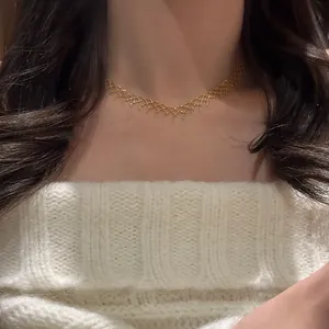 Close-up of a gold mesh lace choker necklace worn by a model with a white sweater
