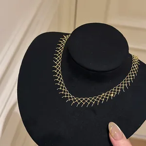 Detailed view of an elegant gold mesh lace choker necklace on a black velvet display