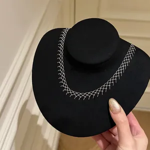 Detailed view of an intricate silver-colored mesh lace necklace on a black display