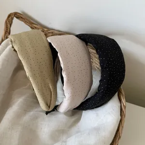 Detailed view of three polka dot padded headbands in olive, beige, and black.