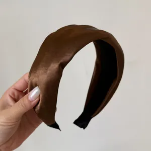 Detail shot of a brown satin padded wide headband featuring an elegant high top design.