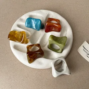 Vue détaillée de plusieurs bagues en résine marbrée de différentes couleurs sur un plateau