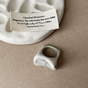 Gros plan d'une bague en résine marbrée irrégulière avec de jolis reflets gris et blancs