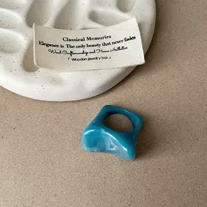 Gros plan d'une bague en résine bleue marbrée irrégulière pour un look mode unique.