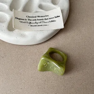 Détail d'une bague unique en résine marbrée verte irrégulière sur une plaque en céramique